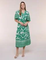 Vestido midi de estilo bohemio en color verde y blanco, con estampa floral, escote en V, cierre frontal con botones, mangas cortas amplias, cintura ajustable con lazo y volado en el bajo.