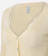 Cardigan de tricot acanalado color beige, de calce ajustado, con mangas largas y escote en V. Cuenta con cierre frontal con botones y detalles de encaje aplicado en el escote y el ruedo.
