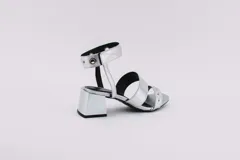 Sandalias negras de cuero con dos tiras horizontales sobre el pie y pulsera al tobillo con ojalillos y tachas. Taco cuadrado de 5 cm.