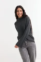 Sweater de punto canalé en color gris oscuro, con cuello alto y mangas estilo oxford ligeramente acampanadas. Presenta un corte holgado y diseño minimalista.