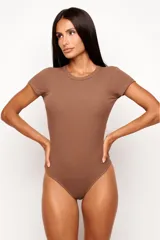 Body de manga corta con cuello redondo, confeccionado en tejido de viscosa con elastano de textura acanalada. Presenta un diseño ajustado al cuerpo con forro frontal para mayor cobertura.
