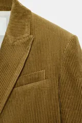 Blazer oversize de pana con cuello solapa y manga larga. Presenta cierre frontal cruzado con botones, bolsillos delanteros y forro interior a tono.