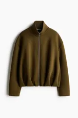 Campera efecto neopreno color verde militar, con cuello chimenea, cierre frontal, hombros caídos y diseño fruncido en el bajo.
