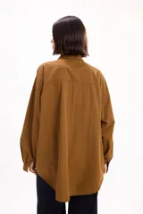 Camisa de corte oversize color marrón, con cuello clásico, cierre frontal de botones y bolsillo en el pecho.