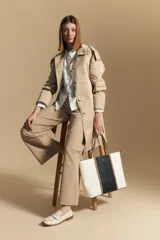 Trench azul marino de corte clásico con cuello amplio, botones frontales grandes en color beige, y detalles en los hombros.