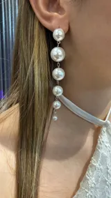 Aros colgantes compuestos por una serie de cinco perlas de tamaño decreciente, unidos por eslabones metálicos plateados.