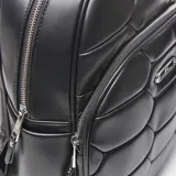 Mochila negra de cuero sintético con diseño acolchado en forma de hexágonos. Tiene un asa de mano en la parte superior, correas regulables para los hombros, herrajes plateados, forro interior textil y un bolsillo interno con cierre.