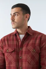 Sobrecamisa de algodón a cuadros color ladrillo, con interior de corderito, cierre con botones, bolsillos tipo cartera y logo en goma. El modelo usa talle M.