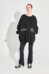 Buzo oversize negro de frisa con cuello redondo, hombros caídos, bolsillos delanteros y estampa serigráfica en delantero y espalda.