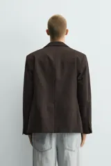 Blazer de corte regular fit confeccionada en tejido con mezcla de lana. Presenta cuello con solapas de pico, cierre frontal de botonadura cruzada, bolsillos con solapa en la cadera y aberturas en la espalda.