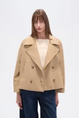 Chaqueta corta estilo peacoat, color beige, con cuello solapa y cierre cruzado de doble botonadura. Presenta un calce holgado y bolsillos laterales.