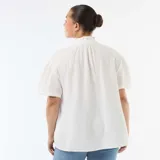 Blusa blanca de gasa de algodón, con cuello fruncido, escote en V con cierre frontal de botones y mangas cortas abullonadas.