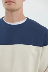 Sweater deportivo de hombre con escote redondo, diseño colorblock con la parte superior en gris claro y el cuerpo y mangas en negro. Presenta puños y cintura elastizados.