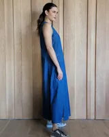 Vestido largo de denim azul, con escote en V, sin mangas, corte holgado, bolsillos laterales y aberturas en los costados de la falda.