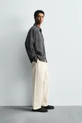 Pantalón de corte regular fit confeccionado en tejido de algodón con textura de espiga. Presenta cintura con pliegues frontales, bolsillos laterales y bolsillos traseros de vivo con botón. Cierre frontal con cremallera y botón.