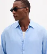 Camisa de corte relajado confeccionada en cambraia de lino puro. Presenta cuello inglés, cierre frontal con botones y mangas largas.