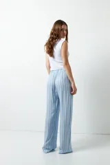 Pantalón de pijama celeste con rayas verticales finas color marrón, con bolsillos laterales y elástico en la cintura.