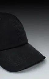 Gorra de béisbol negra, estilo clásico de seis paneles, con visera curva y botón superior. Presenta un tejido de sarga liso.