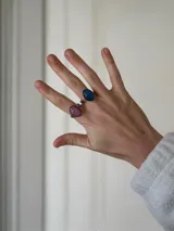 Anillo de acero quirúrgico con diseño de piedra ovalada en tono rosado con textura craquelada.