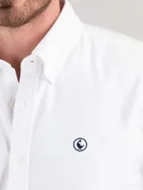Camisa blanca de corte regular fit, cuello button-down, manga larga con puño simple y logo bordado en el pecho. Confeccionada en tejido oxford compuesto por 93% algodón y 7% algodón reciclado.