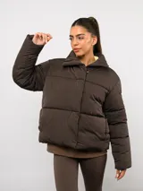 Campera puffer corta Umbro de color negro, con cuello alto, cierre frontal y bolsillos laterales. Presenta un diseño acolchado y logo de la marca bordado en el pecho.