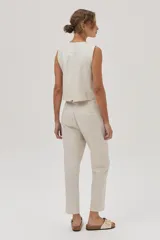 Chaleco sastrero color beige de lino y viscosa metalizado, con cuello en V y cierre con botones.