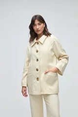 Chaquetón de lana fina sin teñir, con cuello camisero, cierre frontal de botones y bolsillos delanteros. Diseño de corte recto y estructura clásica.