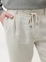 Short de lino orgánico color beige, con ajuste de cordón en la cintura, bolsillos laterales y traseros, y corte relajado.