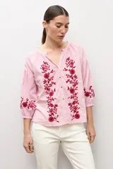 Blusa de manga larga con estampado de rayas verticales en tonos celestes y blancos. Presenta un escote en V con cierre frontal de botones y detalles de bordados florales en color crema en el frente y en los puños.