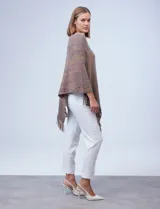 Poncho tejido en hilo soft, con efecto jaspeado multicolor (predominantemente tonos oscuros como azul marino, negro, y toques de violeta y dorado/lurex). Presenta un diseño asimétrico y flecos largos en los bordes.