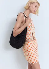 Minifalda de crochet color beige con estampado floral en tonos naranjas, corte recto y bajo festoneado.