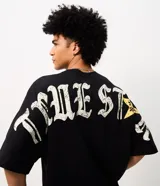 Remera oversized de algodón negro, con cuello redondo y mangas cortas. Presenta un gran estampado en la espalda con la inscripción "True Star" en tipografía gótica y detalles de estrellas.