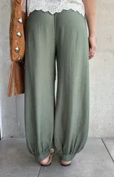 Pantalón tipo babucha de color verde militar, con cintura elástica fruncida y cordón ajustable. Cuenta con diseño amplio y puños elásticos en los tobillos.