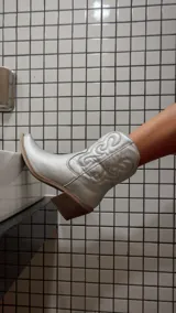 Botas texanas de caña corta en color plateado metalizado, con diseño de costuras decorativas en el lateral y taco cuadrado de madera.