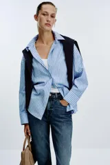 Jeans de mujer, tiro alto, corte Mom Fit con pierna slim y largo tobillero. Denim azul medio con efecto desgastado y lavado. Presenta cinco bolsillos y cierre frontal con cremallera y botón.