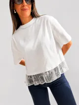 Remera de algodón de corte holgado y diseño liso, con cuello redondo y mangas cortas. Presenta un detalle de volado de encaje en el ruedo inferior.