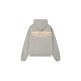 Hoodie oversize de color gris melange, de la marca Eme Studios, con capucha y bolsillo tipo canguro. Presenta un estampado gráfico en la espalda en tonos claros con tipografía y detalles distintivos de la marca.
