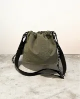 Bandolera tipo saco color verde militar, confeccionada en tela impermeable con textura arrugada. Cuenta con cierre mediante cordón ajustable y correa larga regulable en color negro con detalles reflectantes.