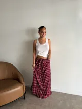 Pollera larga de fibrana color bordó con estampado de lunares blancos, tiro alto y corte amplio.