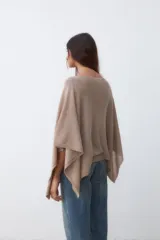 Poncho de tejido de punto color beige con hilo lurex plateado, de corte asimétrico y mangas amplias.