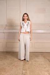 Pantalón palazzo negro de lino con cintura elástica, bolsillos laterales y cinturón con hebilla circular.