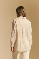 Camisa blanca de manga larga con textura calada o bordada, cuello camisero y corte holgado.