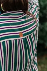 Camisa de fibrana con diseño de rayas verticales rojas y blancas, corte oversize, mangas largas abullonadas, cuello camisero y bolsillos frontales con solapa.