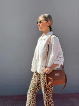 Cartera tipo bandolera de cuero color tostado, con solapa frontal, cierre principal y herrajes metálicos. Incluye dos correas desmontables, una corta para llevar al hombro y una larga ajustable para usar cruzada.