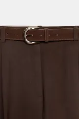 Pantalón de tiro alto con pinzas delanteras, bolsillos laterales y cierre frontal con cremallera y gancho. Incluye un cinturón a contraste con hebilla metálica.