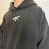 Canguro con capucha de corte oversize y efecto lavado, color gris oscuro. Presenta un estampado pequeño en el pecho con el dibujo de un auto y la inscripción 'EST. VCP 2015'. Cuenta con bolsillo frontal tipo canguro y etiqueta pequeña en el puño.
