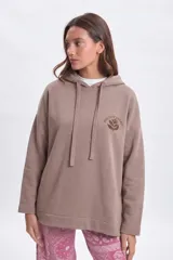 Canguro deportivo de corte oversize en color taupe, con capucha y estampa gráfica en la espalda con diseño floral y la frase Positive Energy Is Contagious.
