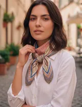 Pañuelo cuadrado de satén con estampado geométrico y floral en tonos beige, rosa y azul. Presenta un diseño con bordes definidos y motivos ornamentales.