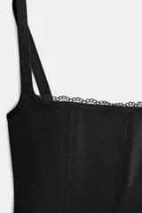 Top corsé negro con escote cuadrado, tirantes finos y detalle de encaje a tono en el escote. Confeccionado en tejido elástico con varillas interiores.