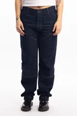 Pantalón de jean azul oscuro, corte recto, con refuerzos en las rodillas y bolsillos delanteros con detalle de costuras a la vista.